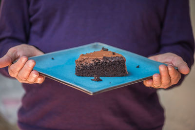 Midsection of man holding chocolate cake in plate