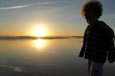 Woman standing at beach during sunset