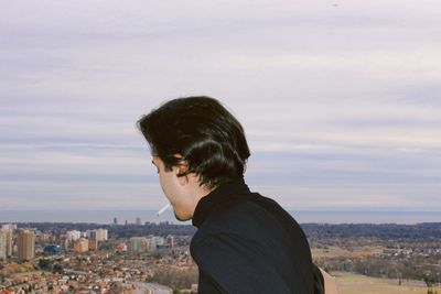 Man smoking cigarette against cityscape