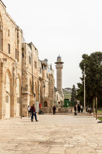 People walking in historic building against clear sky