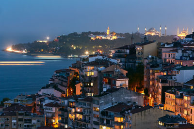 High angle view of illuminated buildings by sea against sky