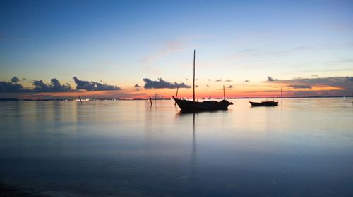 Sailboats in sea against sky during sunset