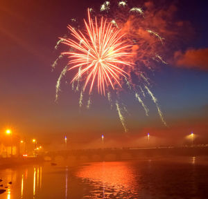 Firework display over river against sky at night