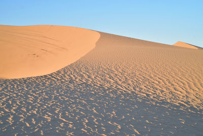 Scenic view of desert against clear blue sky