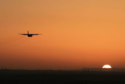 Airplane flying in sky at sunset