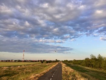 Road amidst field against sky