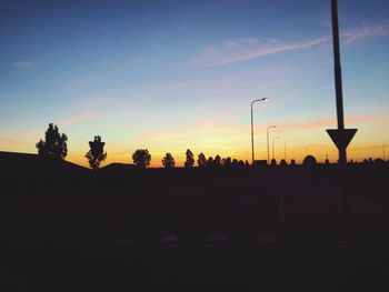 Silhouette street against sky during sunset