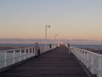 Pier over sea against sky during sunset