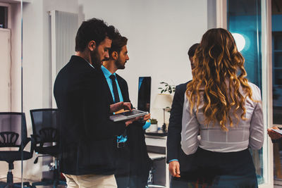 Side view of female friends using digital tablet while standing in office