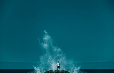 Man standing in sea against clear blue sky