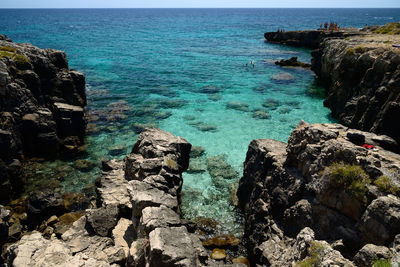 Rocks on sea shore against blue sky