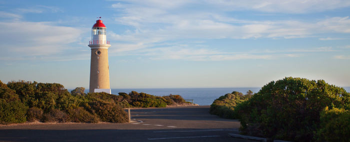 Lighthouse by sea against sky