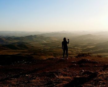 Man and woman standing on mountain against clear sky