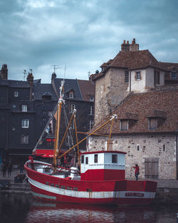 Sailboats moored on sea against buildings in city