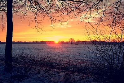 Scenic view of landscape against dramatic sky during sunset