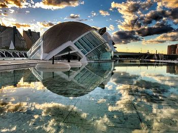 Reflection of cityscape on bridge against sky during sunset