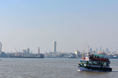 Nautical vessel on sea by buildings against clear sky