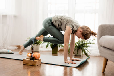 Beautiful young woman doing exercises and doing yoga at home