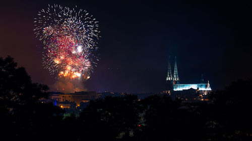 Illuminated fireworks by historic cathedral against sky at night