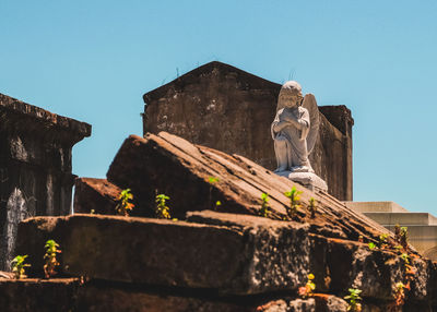 A statue of an angel sits on decaying graves and tombstones at a cemetery in new orleans, la against 