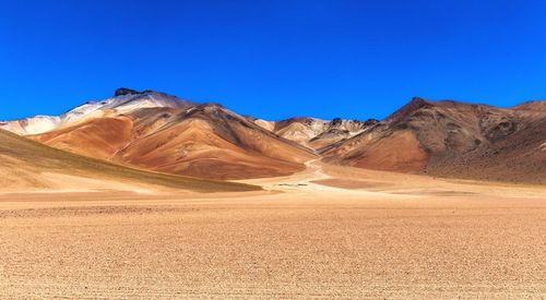 Scenic view of desert against clear blue sky