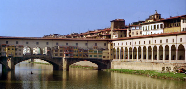 Arch bridge over river against buildings in city