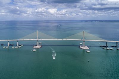 Scenic view of suspension bridge over sea against sky