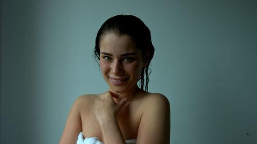 Portrait of smiling young woman against gray background