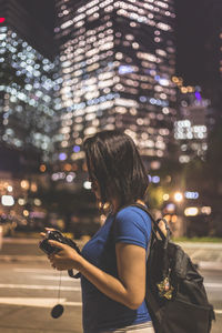 Full length of woman standing on illuminated city at night