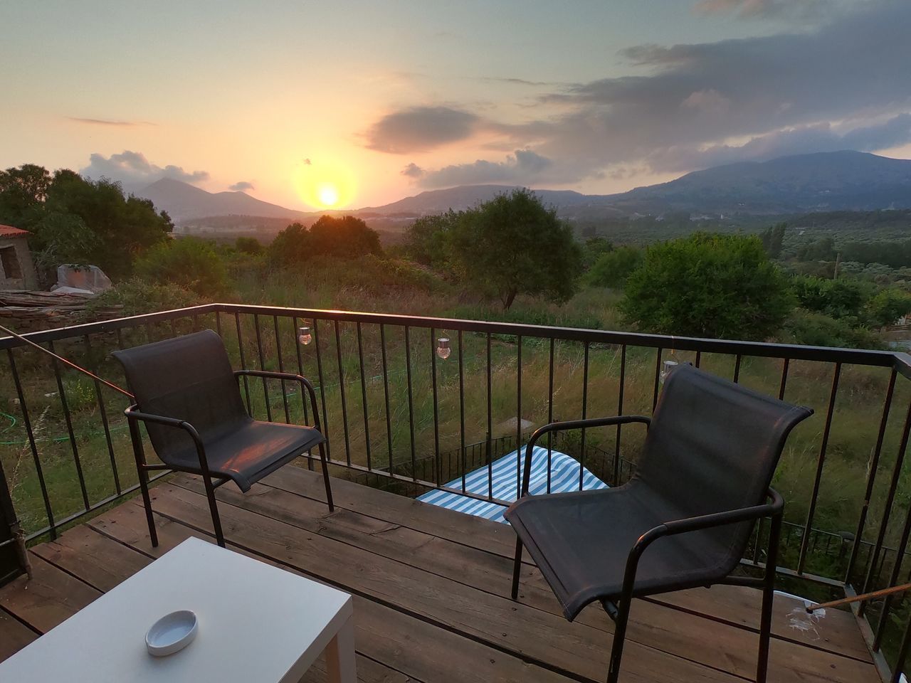 EMPTY CHAIRS AND TABLES BY SWIMMING POOL DURING SUNSET