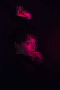 Close-up of young woman against black background