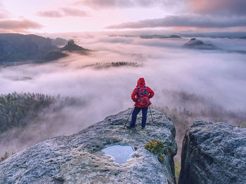 Scenic view of girl hiking in mountains, against daybreak sky
