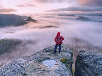 Hike with backpack and trekking sticks at edge of dangerous and popular viewpoint above deep valley