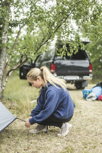 Teenage girl pitching tent at camping site