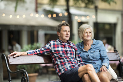 Senior couple sitting on bench watching something