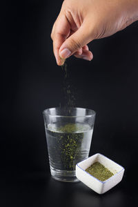 Close-up of hand holding drink against black background