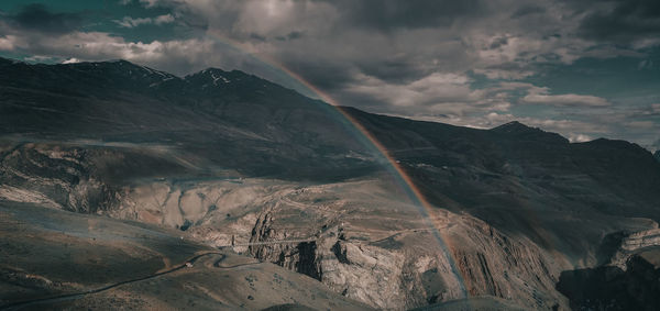 Scenic view of rainbow over mountains against sky