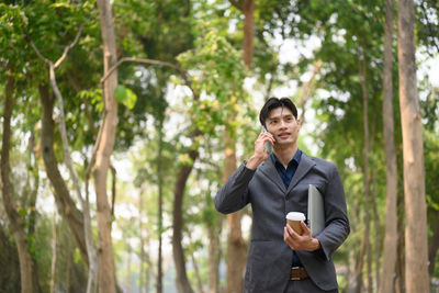 Young man standing against trees