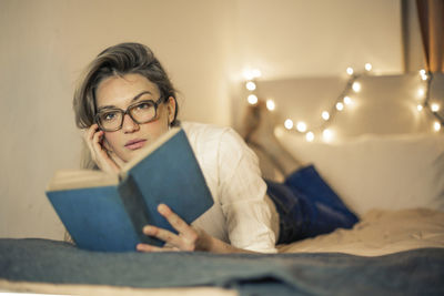 Young woman reads a book on a bed