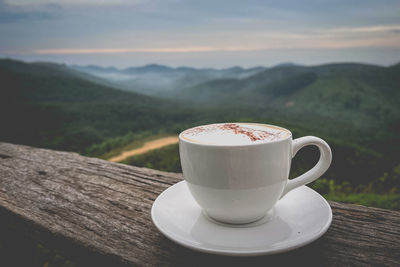 Coffee cup on table against mountains