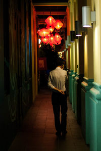 Full length of man hanging in illuminated shop