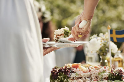 Close-up of woman putting cake on plate