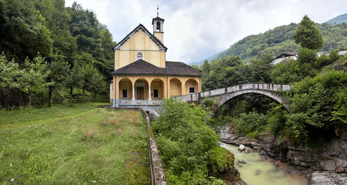 Arch bridge amidst trees and building against sky