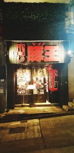 Information sign on illuminated street by building at night