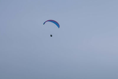 Low angle view of person paragliding against clear sky