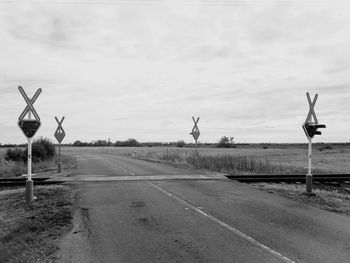 Street lights on road by field against sky