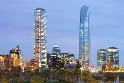 Illuminated buildings in city against blue sky