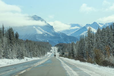 Road amidst snowcapped mountains against sky