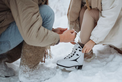 Man tying skates to his girlfriend. winter romance, love, wintertime