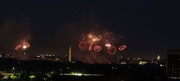 Firework display in city against sky at night